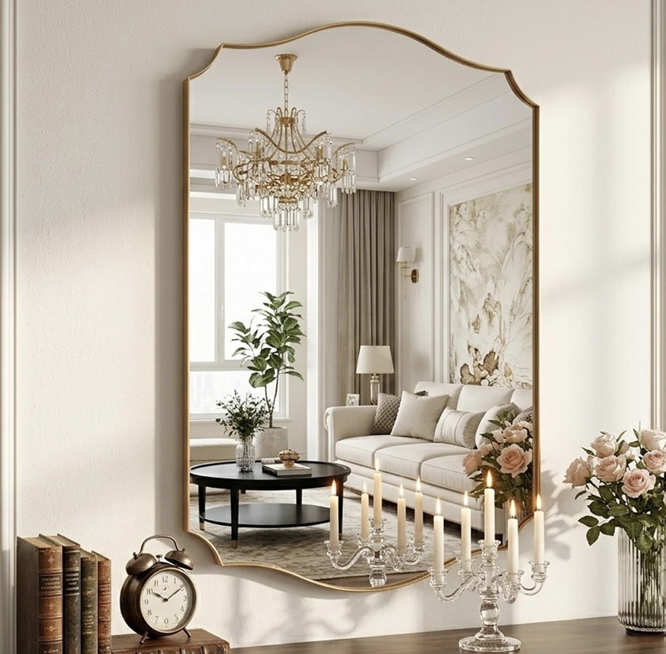 Entrada con Espejo — Residencial · Recibidor Recibidor elegante con gran espejo arqueado de marco dorado que refleja la sala, consola de madera con libros antiguos, reloj vintage, candelabro de cristal y rosas en jarrón de vidrio